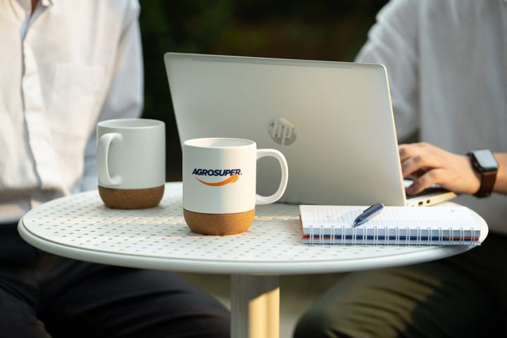 Taza con el logo de Agrosuper junto a un computador